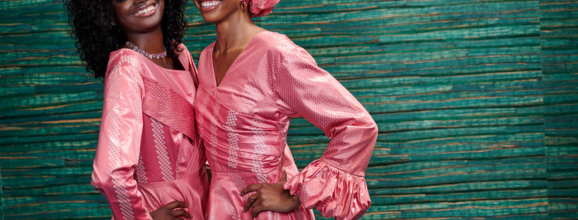 two woman smiling in coral dresses
